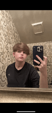 a young man taking a selfie with his phone in front of a mirror