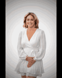 a woman wearing a white dress and earrings smiles for the camera