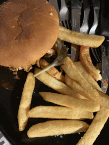 a hamburger and french fries on a plate with knives and forks