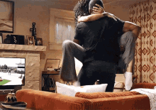 a man is carrying a woman in his arms in a living room in front of a television .