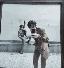 a man in a suit is taking a picture of himself in the mirror