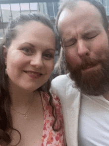 a man with a beard and a woman with long hair are posing for a picture with their eyes closed