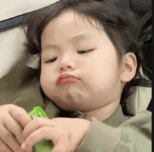 a little girl is making a funny face while holding a green object .