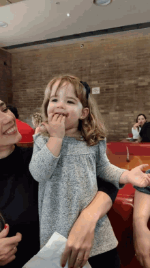 a little girl is being held by a woman in a restaurant with a no smoking sign on the wall