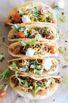 a stack of tacos with meat lettuce and tomatoes