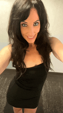 a woman in a black dress is smiling and taking a picture