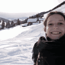 a woman is smiling in front of a snowy landscape