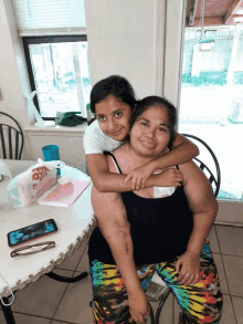 a little girl is sitting on a woman 's shoulders in front of a table