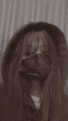 a woman with long hair is wearing a black mask and a hoodie .