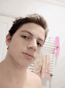 a shirtless young man is taking a selfie in a bathroom .