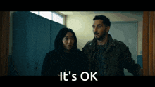 a man and a woman are standing in a hallway with the words " it 's ok " on the bottom