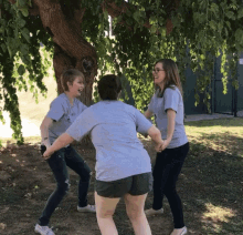 three women holding hands in front of a tree with one wearing a t-shirt that says ' i love you ' on it