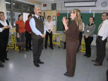 a group of people standing in a classroom with a clock on the wall above them