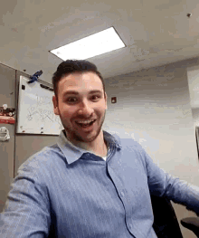 a man in a blue shirt is smiling in front of a whiteboard that says ' i love you ' on it