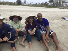 a man wearing a shirt that says ' loving ' on it sits on the beach