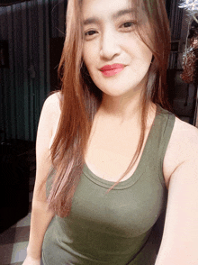 a woman wearing a green tank top is smiling for the camera