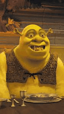 shrek from shrek is sitting at a table with a bowl of soup and wine glasses .