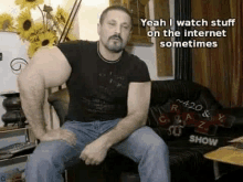 a man with a very large arm is sitting on a couch and talking .