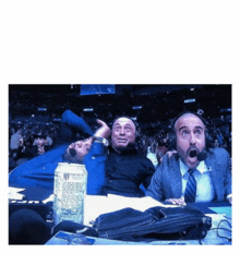 a group of men sitting in a stadium with a can of monster energy drink