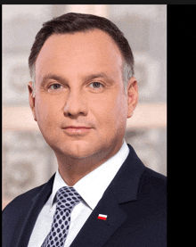 a man in a suit and tie has a red white and blue flag pinned to his jacket lapel