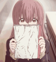 a girl with long hair is holding a book in front of her face