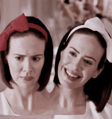 two women wearing headbands are smiling and looking at the camera