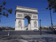 a car is parked in front of the triumphal arch on a sunny day