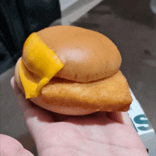 a person is holding a chicken sandwich with cheese on top