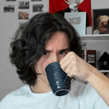 a man with long hair is drinking from a blue cup