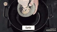 a person is grinding garlic into a mortar and pestle in a pan .