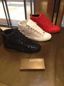 three pairs of balenciaga shoes are on display on a wooden table