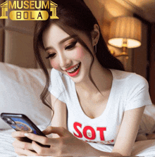 a woman wearing a white shirt with the word sot on it looks at her phone