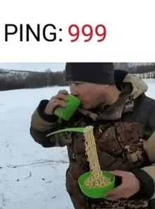 a man is eating noodles in the snow while drinking from a green cup .