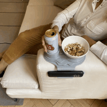 a woman is sitting on a couch holding a can of stella artois beer