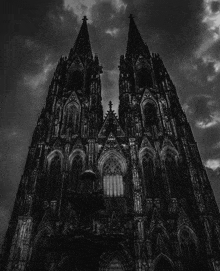 a black and white photo of a cathedral with a cloudy sky behind it