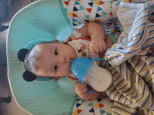 a baby wearing a shirt that says friends is drinking from a blue cup