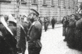 a black and white photo of a man in a uniform standing in front of a crowd of people .