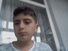 a young boy looks at the camera while wearing a blue and white shirt