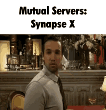 a man sitting at a table with mutual servers synapse x above him