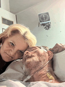 a man is laying in a hospital bed with his head on his wife 's lap