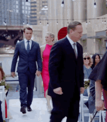 a man in a suit and tie walks down the aisle holding hands with a woman in a pink dress