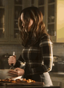 a woman in a plaid shirt is cooking in a kitchen