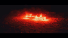 a group of people standing in a circle with red lights behind them