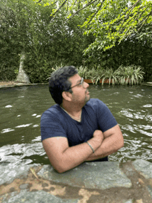 a man in a blue shirt is standing in a pool of water with his arms crossed