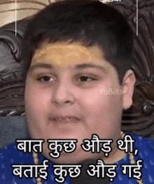 a young boy with a bandage on his forehead is sitting on a couch with a caption in a foreign language .