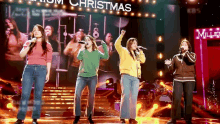 a group of women singing on a stage with a sign that says christmas