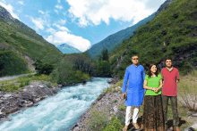 a group of people standing next to a river in a valley