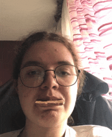 a girl wearing glasses holds a piece of chocolate in her mouth