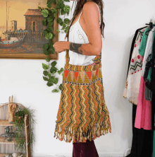 a woman in a white tank top is standing in front of a painting of a boat