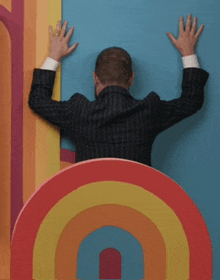 a man in a suit leans against a wall with his hands on it